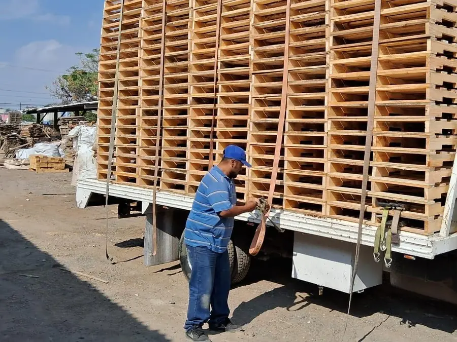 Trabajador de JMO asegurando un camión cargado de tarimas nuevas
